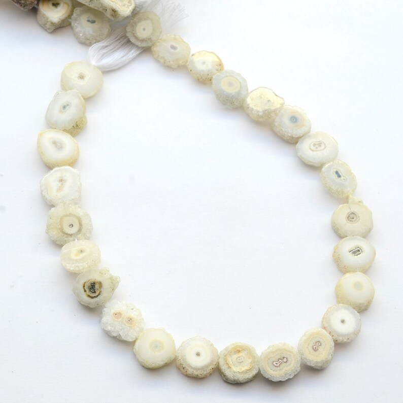 May include: A strand of white agate beads with a crystal-like appearance. The beads are round and have a natural, rough texture.