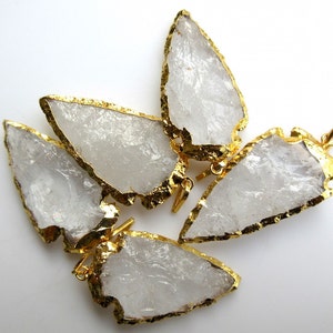 May include: Four clear quartz arrowhead pendants with gold-plated edges. The pendants have a raw, natural look and are perfect for jewelry making.