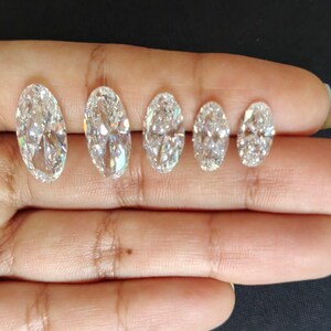 May include: Five clear, colorless, oval-cut gemstones arranged in a row by size from largest to smallest. Each stone features a faceted surface that reflects light, creating a brilliant, sparkling appearance with multiple internal light refractions.