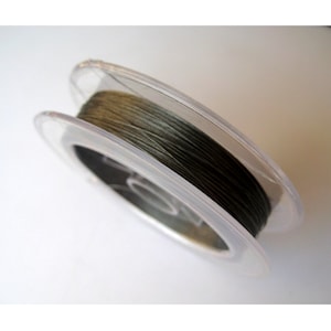 May include: A spool of dark green fishing line in a clear plastic container.
