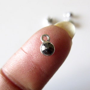 Peut inclure: Un charme en argent avec une pierre précieuse noire facetée et une petite boucle pour l'attacher à un bracelet ou un collier.