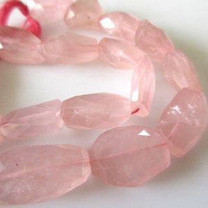 May include: A strand of pale pink rose quartz beads, each bead is faceted and has a slightly irregular oval shape.