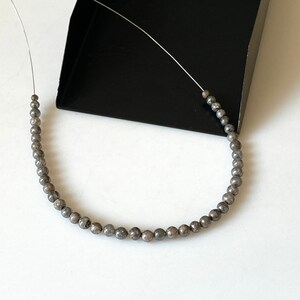 May include: A strand of silver-toned beads with a speckled finish, strung on a thin wire.
