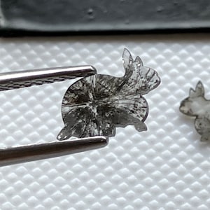 May include: A clear, gray, crystal rabbit figurine with intricate details. The rabbit is carved from a single piece of crystal and has a delicate, translucent appearance.