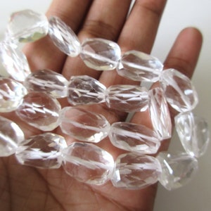 K&ouml;nnte beinhalten: Eine Str&auml;hne aus klaren Quarzkristallperlen, facettiert und oval geformt. Die Perlen sind auf einem durchsichtigen Faden aufgereiht und haben einen Durchmesser von etwa 10 mm.