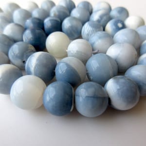 May include: A strand of blue and white opal beads. The beads are round and have a smooth, polished finish.