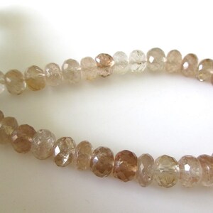 May include: A strand of faceted, translucent brown gemstone beads. The beads are strung on a white thread and are approximately 6mm in diameter.