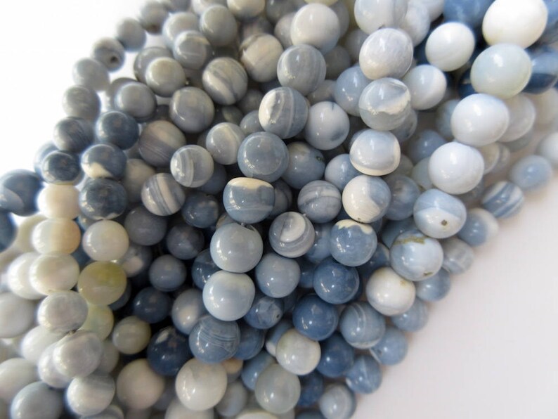 May include: A strand of blue and white agate beads. The beads are round and have a smooth, polished finish. They are perfect for making jewelry or other crafts.