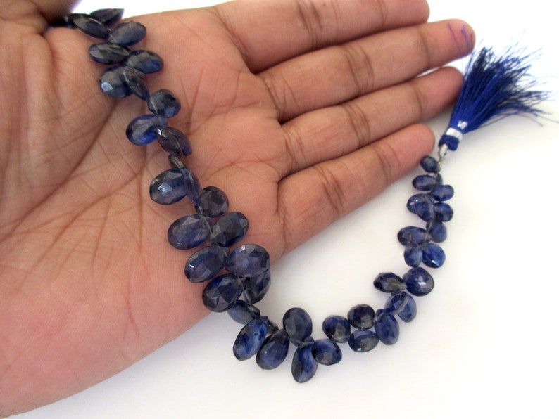 May include: A strand of dark blue gemstone beads, oval shaped, with a tassel at the end. The beads are strung on a thin wire.