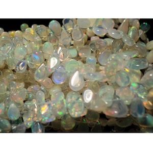 May include: A close-up of a pile of white opal gemstone chips. The chips are iridescent and have a pearlescent sheen.