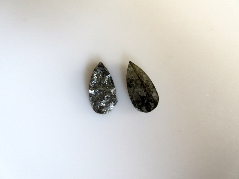 May include: Two teardrop-shaped black and silver stones with a rough, textured surface.