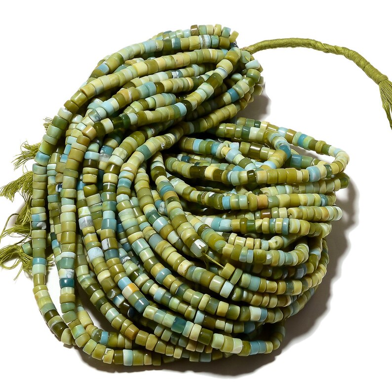 May include: A strand of green and blue gemstone beads. The beads are small and round, and they are strung together on a thin thread. The beads are a mix of light and dark green, with some blue accents.