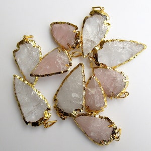 May include: A group of eight arrowhead-shaped pendants made of clear and rose quartz with gold-toned metal accents.