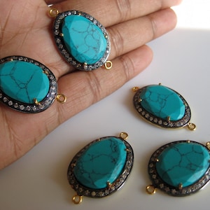 May include: Four turquoise oval-shaped gemstone connector charms with gold-tone accents and a silver-tone bezel setting. Each charm has a clear crystal halo around the turquoise stone and two gold-tone jump rings.