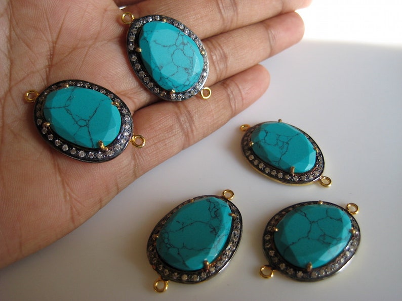 May include: Four turquoise oval-shaped gemstone connector charms with gold-tone accents and a silver-tone bezel setting. Each charm has a clear crystal halo around the turquoise stone and two gold-tone jump rings.