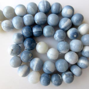 May include: A strand of blue and white opal beads. The beads are round and have a smooth, polished finish.