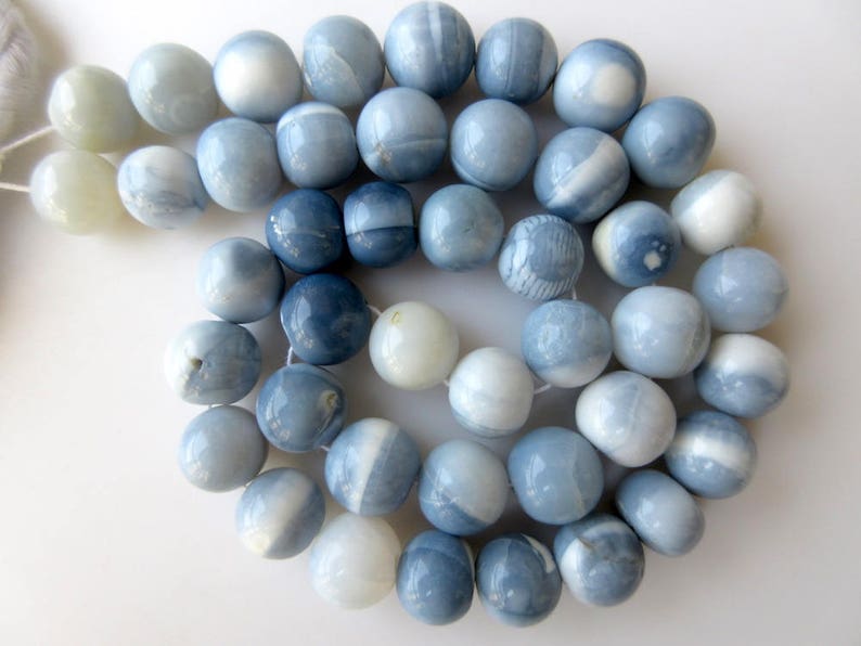 May include: A strand of blue and white opal beads. The beads are round and have a smooth, polished finish.