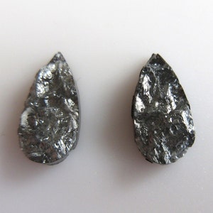 May include: Two teardrop-shaped black stones with a rough, textured surface.