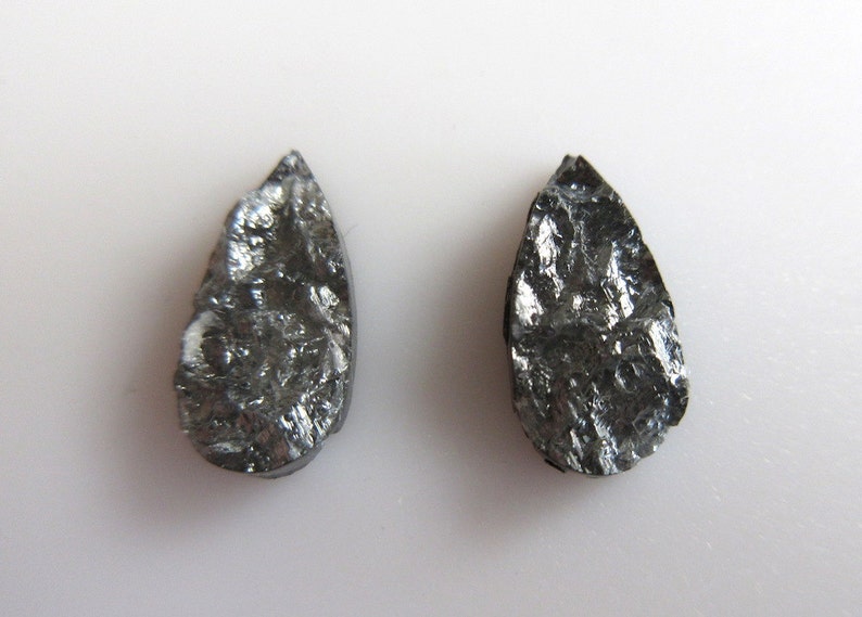 May include: Two teardrop-shaped black stones with a rough, textured surface.