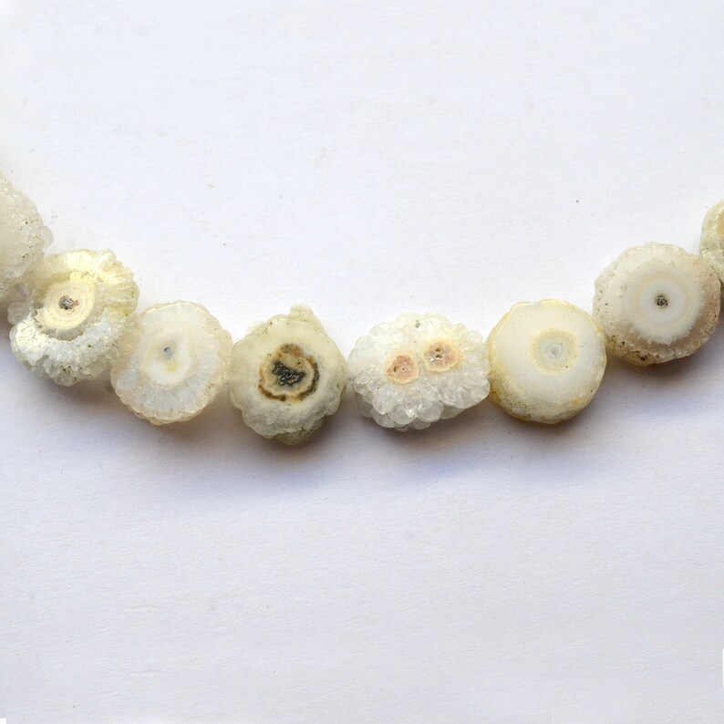 May include: A strand of white agate beads with a crystal-like texture. The beads are round and have a natural, organic look.