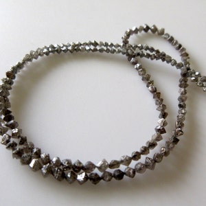May include: A strand of grey, faceted diamond beads. The beads are strung on a thin wire and are arranged in a circular pattern.