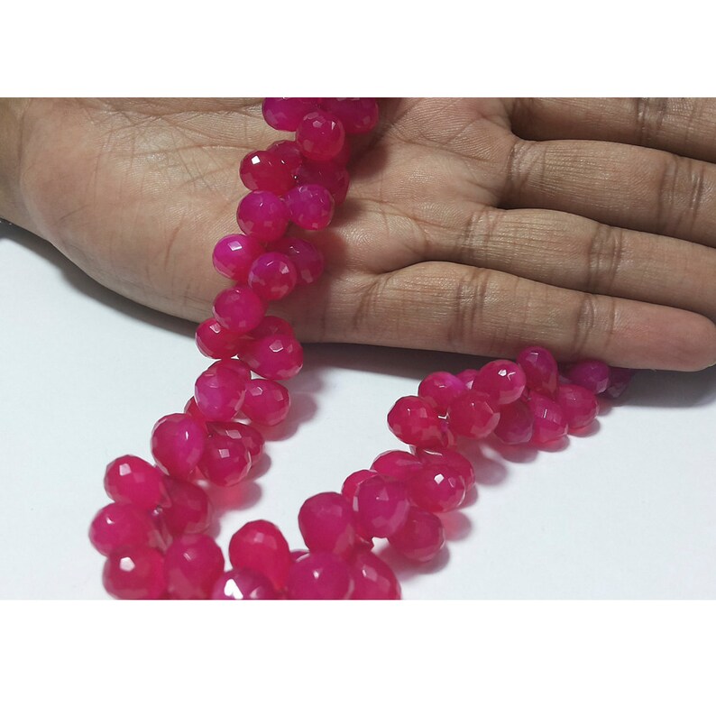 May include: A strand of pink faceted gemstone beads. The beads are round and have a smooth, polished finish.