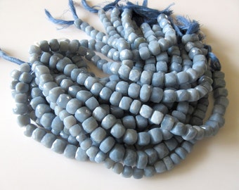 Puede incluir: Una hebra de cuentas de piedras preciosas azul claro, cada cuenta está facetada y tiene una forma cuadrada. Las cuentas están enhebradas en un cordón delgado y están listas para ser utilizadas para la elaboración de joyas.