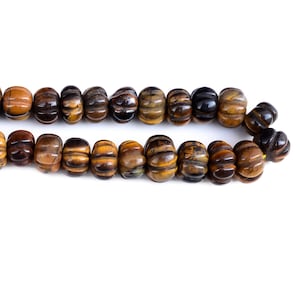 May include: A strand of brown and gold tiger's eye beads with a ribbed texture.