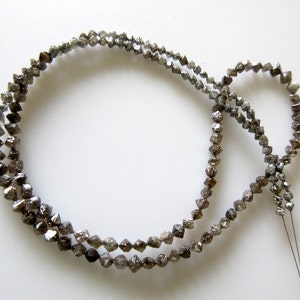 May include: A strand of grey, faceted, diamond beads strung on a thin wire. The beads are small and have a rough, natural texture.