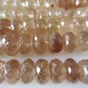 May include: A strand of faceted sunstone beads in shades of brown and gold. The beads are round and have a smooth, polished finish.