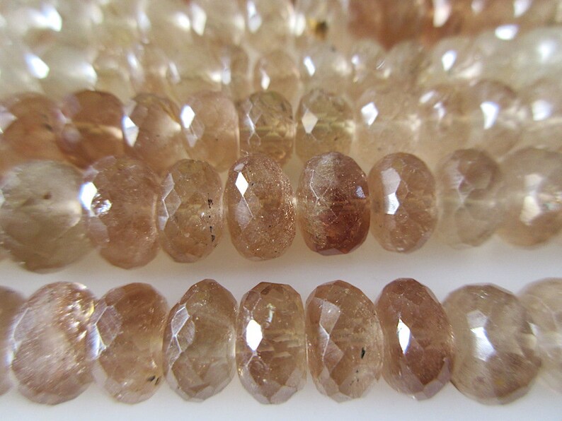 May include: A strand of faceted sunstone beads in shades of brown and gold. The beads are round and have a smooth, polished finish.