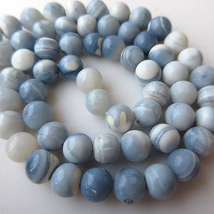 May include: A strand of light blue and white opal beads. The beads are round and have a smooth, polished finish.