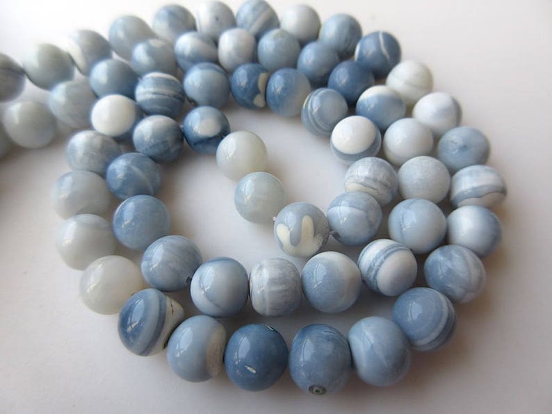 May include: A strand of light blue and white opal beads. The beads are round and have a smooth, polished finish.