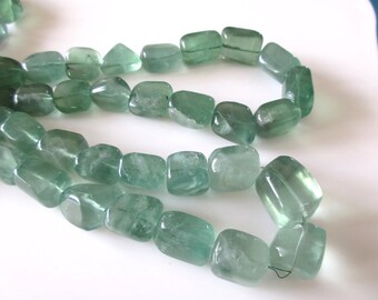 May include: A strand of light green gemstone beads, each bead is a smooth, faceted, rectangular shape.