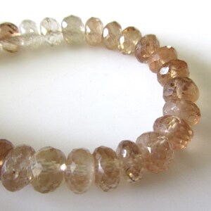 May include: A strand of faceted brown and clear gemstone beads. The beads are round and have a smooth, polished finish.
