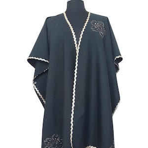 Linen  cape features hand embroidery gold trim  and flowers, with side slits which under arm snap closure  to create optional wide elbow sleeves.
