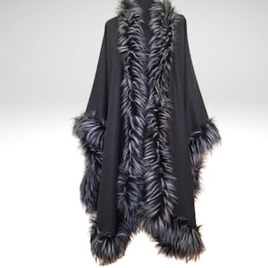 May include: A dark grey cape with faux fur trim. The cape has a wide collar and cuffs trimmed with long, grey and white faux fur. The cape is displayed on a mannequin against a plain background.
