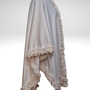 A side view of the Ivory cashmere cape, with handmade lavish trim. elegant shawl wrap with seamless circular cut, flowing silhouette, one size.