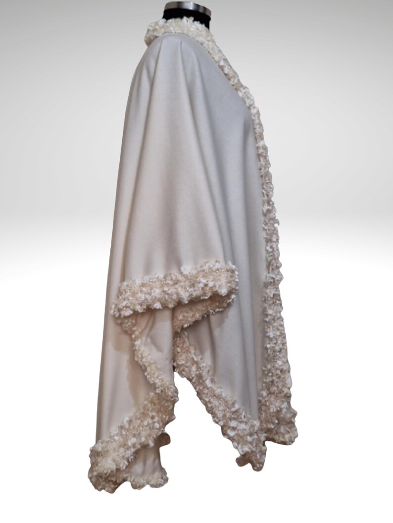 A side view of the Ivory cashmere cape, with handmade lavish trim. elegant shawl wrap with seamless circular cut, flowing silhouette, one size.