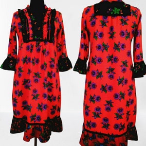 A red vintage style  dress with a floral print and black lace trim. The dress has long sleeves with bell cuffs and a gathered neckline.
