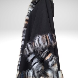 May include: Black hooded cape with faux fur trim in shades of gray, white, and tan. The cape is made of a soft, flowing fabric and features a generous hood. The faux fur trim adds a touch of luxury and warmth to this outerwear.