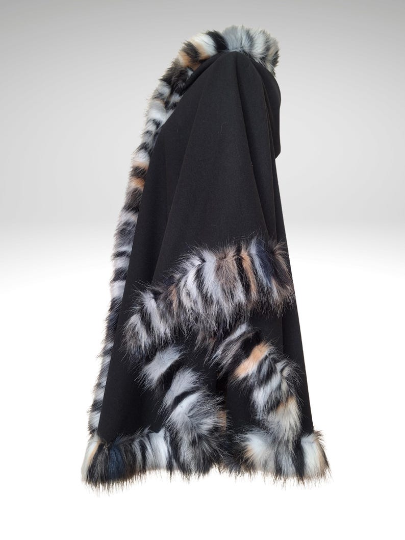 May include: Black hooded cape with faux fur trim in shades of gray, white, and tan. The cape is made of a soft, flowing fabric and features a generous hood. The faux fur trim adds a touch of luxury and warmth to this outerwear.