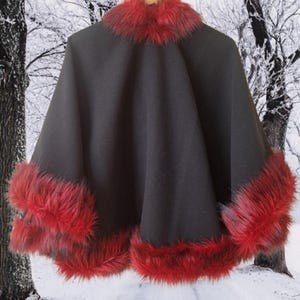 Bold and elegant black cape with red fur trim, photographed in a snowy forest background — a handcrafted piece symbolizing warmth, femininity, and style.”