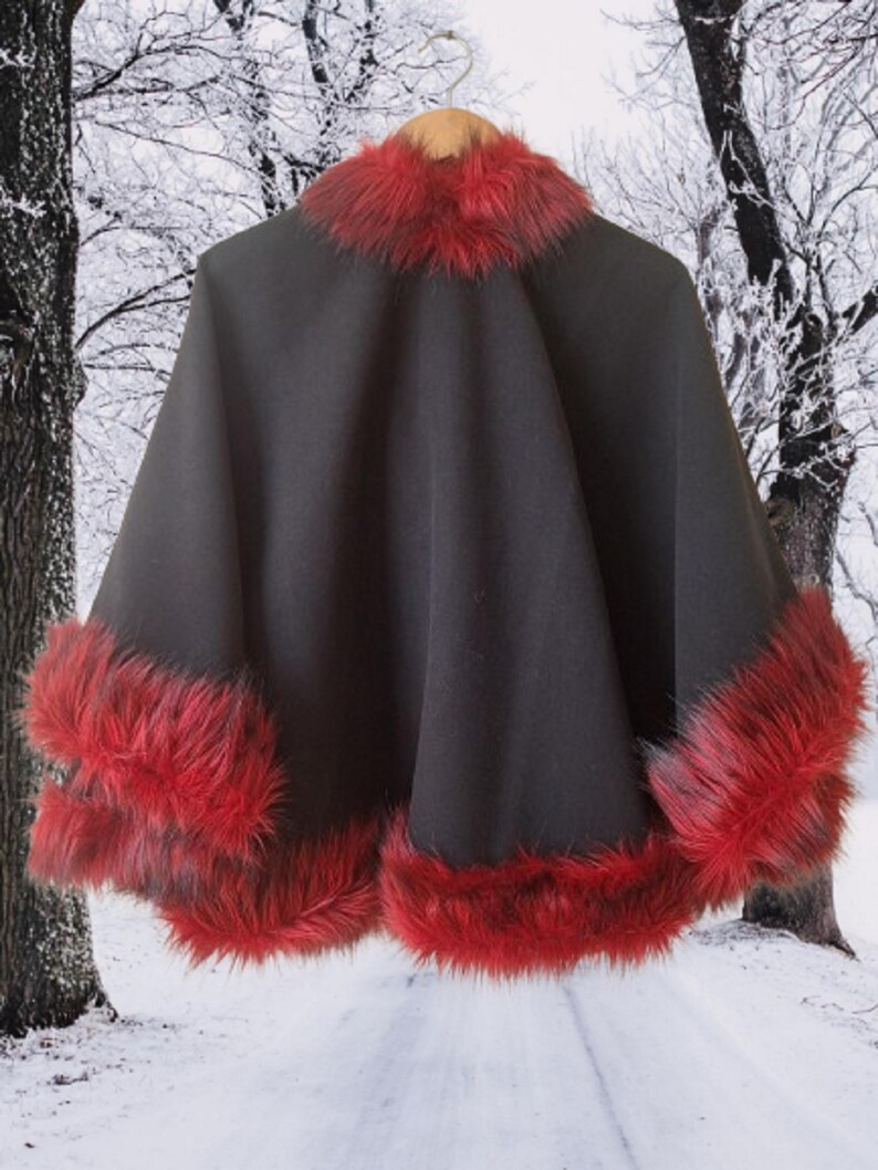 Bold and elegant black cape with red fur trim, photographed in a snowy forest background — a handcrafted piece symbolizing warmth, femininity, and style.”