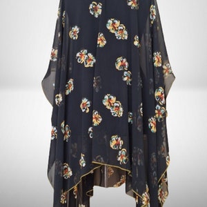 Puede incluir: Kimono negro de gasa transparente con estampado floral en amarillo, rojo y verde. El kimono tiene un ribete de crochet amarillo alrededor del escote.
