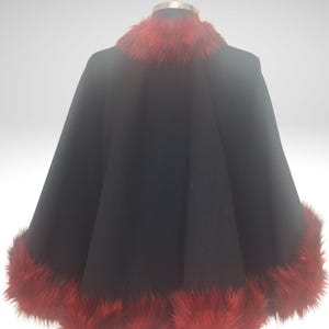 Black Alpaca half cape with red fur is displayed on a mannequin against a white background. The cape is a statement piece