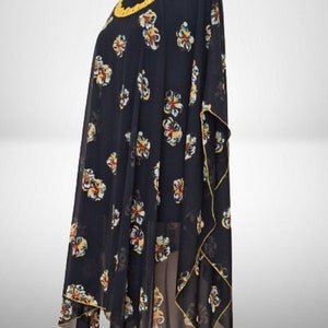 Puede incluir: Una t&uacute;nica negra transparente con estampado floral amarillo y cuello de ganchillo amarillo.