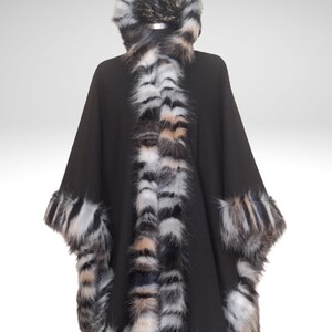 May include: A black cape with faux fur trim and hood. The trim features a mix of black, white, and tan stripes. The hood is also trimmed with the same faux fur. The cape is designed to be worn over the shoulders.