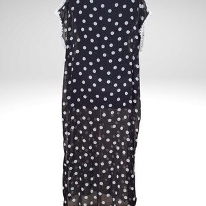 May include: Black and white polka dot dress with white lace trim. The dress is a flowing, lightweight garment with a round neckline and short sleeves. The dress is displayed on a mannequin.