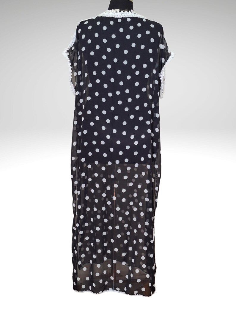 May include: Black and white polka dot dress with white lace trim. The dress is a flowing, lightweight garment with a round neckline and short sleeves. The dress is displayed on a mannequin.